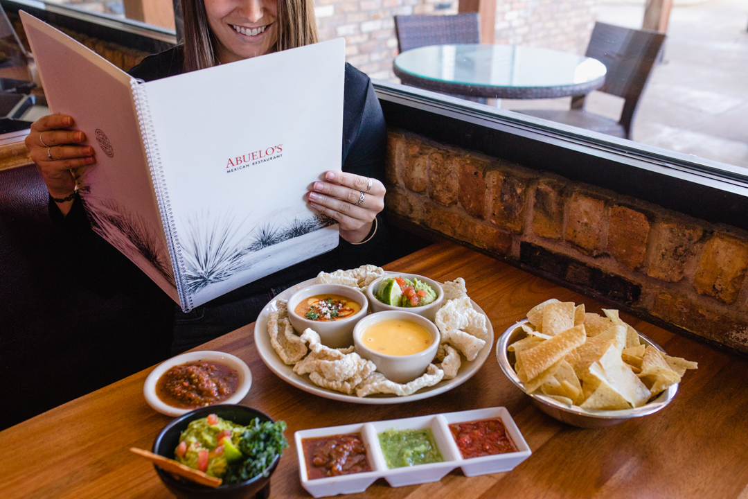 Customer holding Abuelo's menu with appetizers on the table